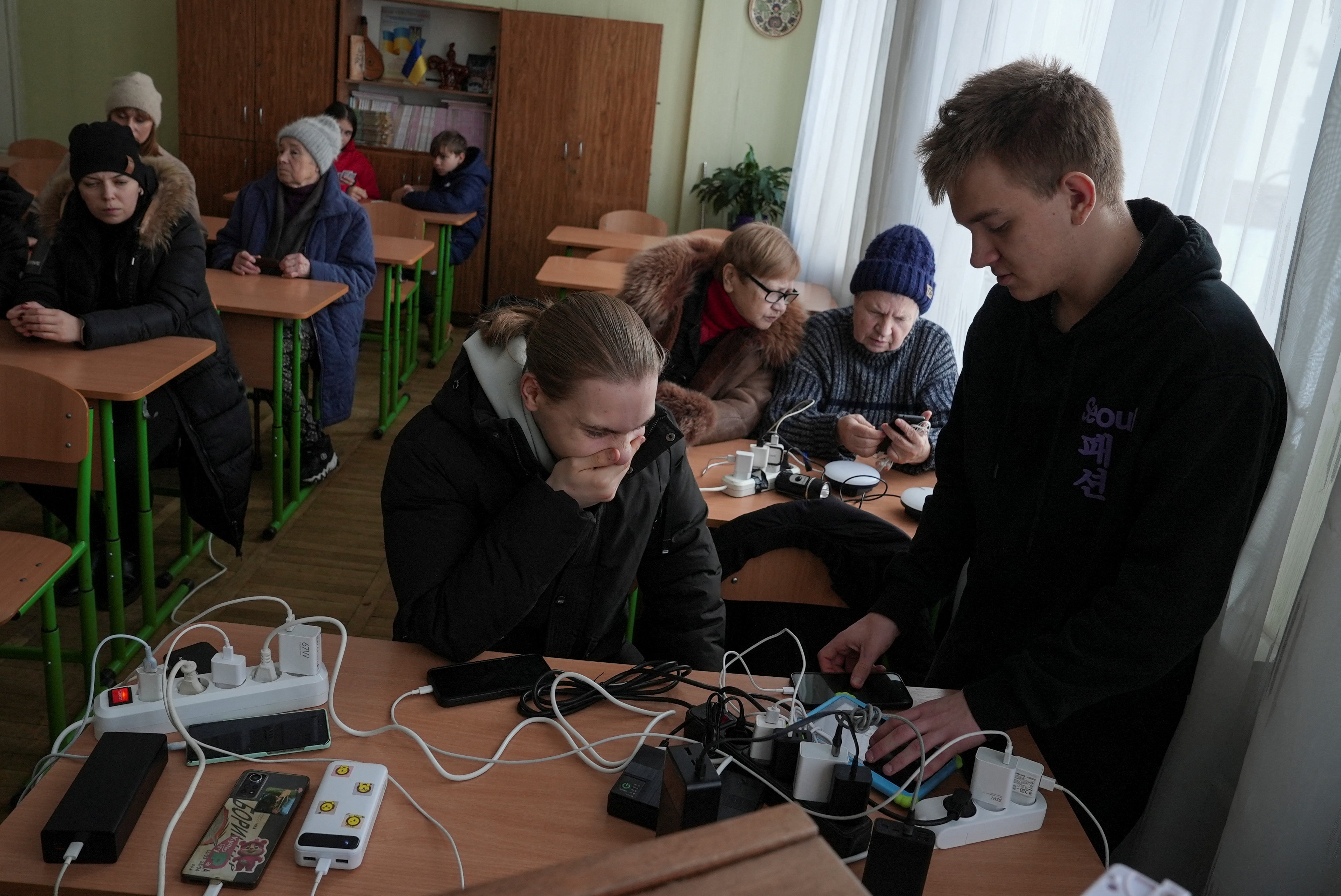 Residents charge theirdevices inside a school classroom turned into a humanitarian aid point during a power blackout in Kyiv