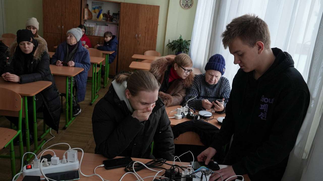 Residents charge theirdevices inside a school classroom turned into a humanitarian aid point during a power blackout in Kyiv