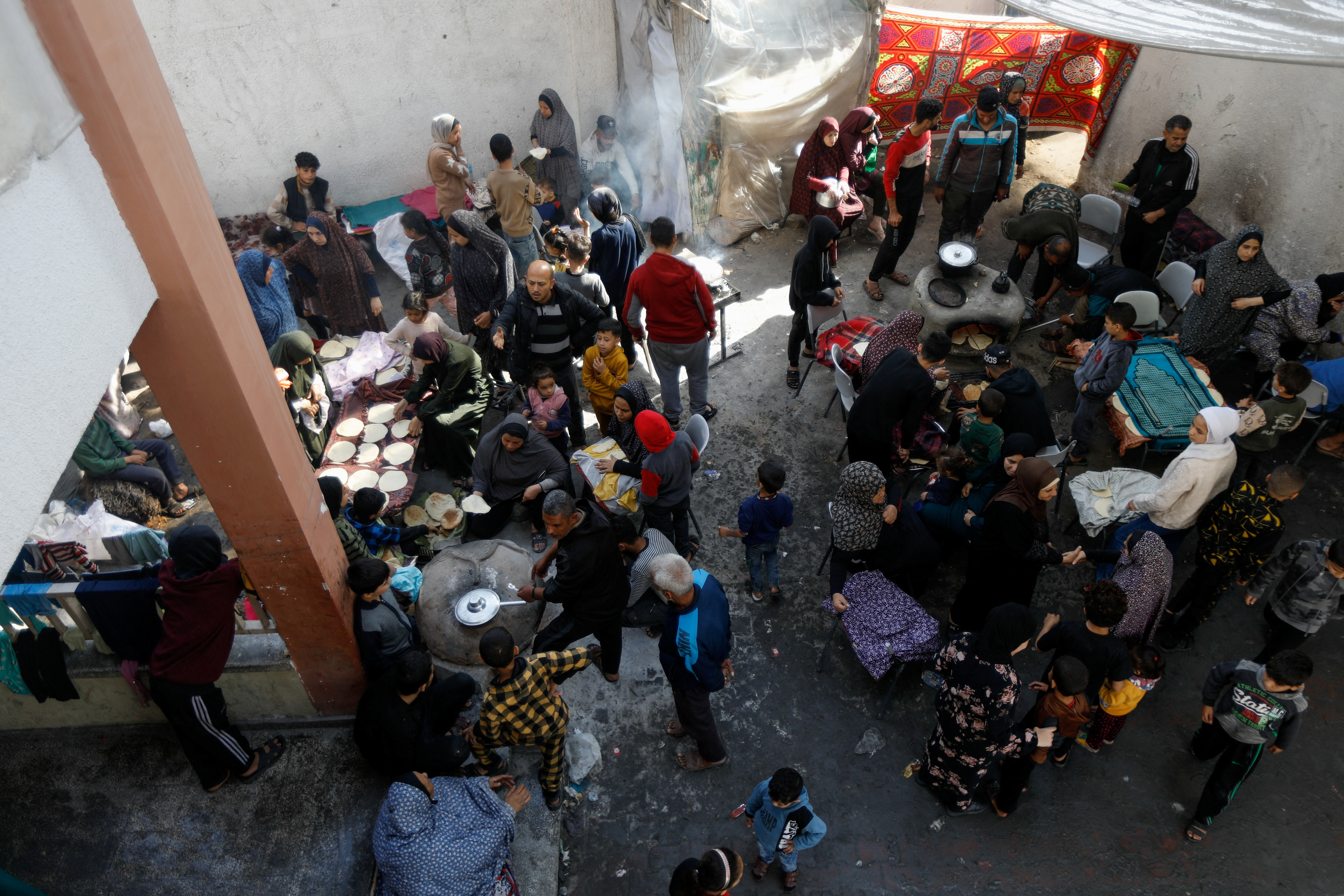 Displaced Palestinians cook at a school sheltering people who fled their houses due to Israeli strikes, in Rafah