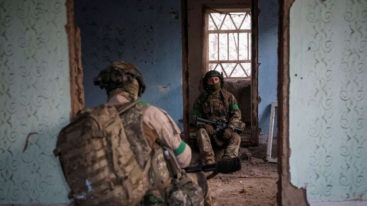Ukrainian servicemen hide from a Russian combat drone in a building damaged by Russian military strike in the frontline town of Kostiantynivka