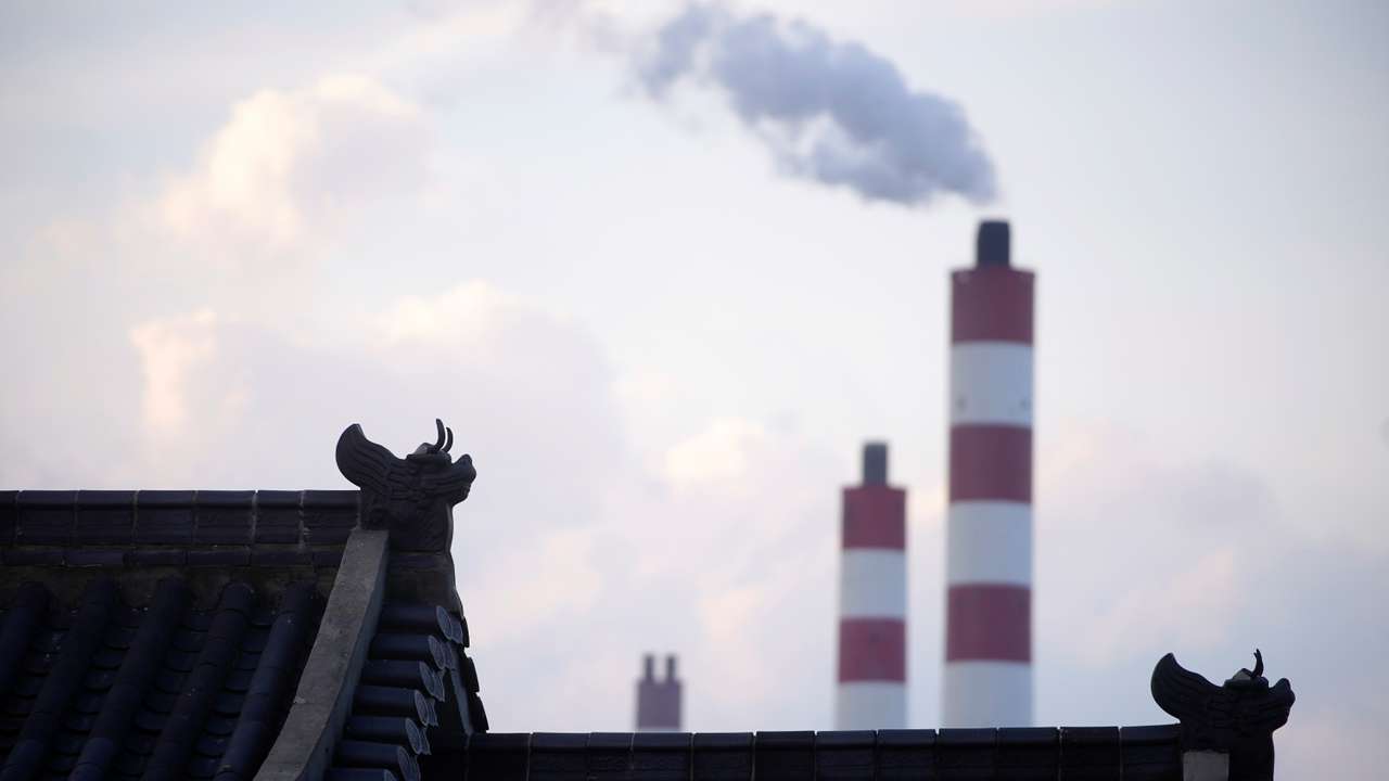 Chimneys of a coal-fired power plant are seen behind a gate in Shanghai