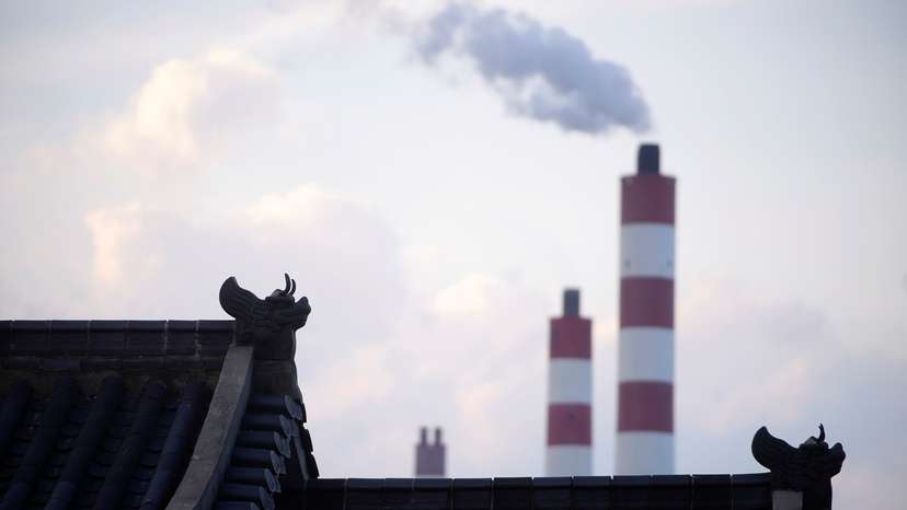 Chimneys of a coal-fired power plant are seen behind a gate in Shanghai