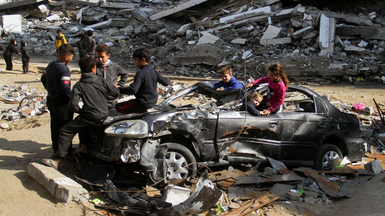Palestinian children play in a destroyed car near the rubble of houses destroyed in previous Israeli strikes, amid ceasefire negotiations with Israel, in Gaza City
