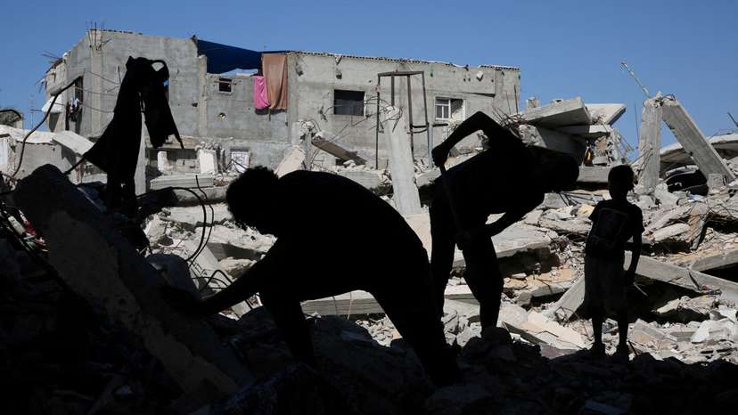 FILE PHOTO: Palestinians remove the rubble of houses destroyed by Israeli strikes, in Khan Younis