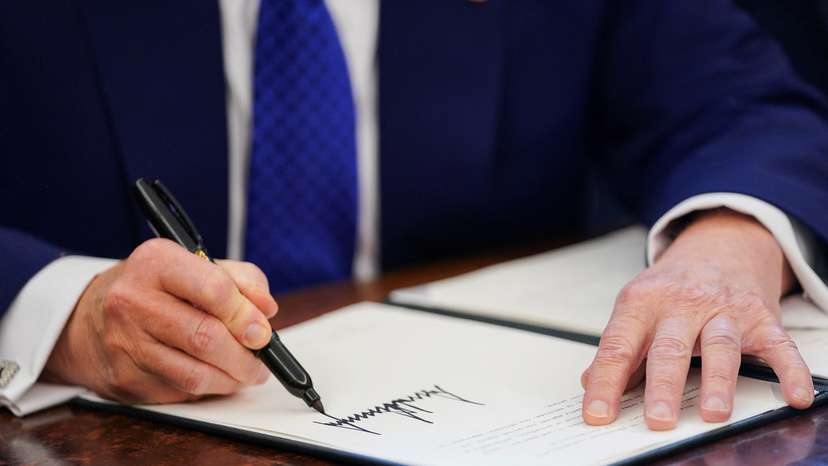 U.S. President Donald Trump signs an executive order in the Oval Office at the White House in Washington, D.C.