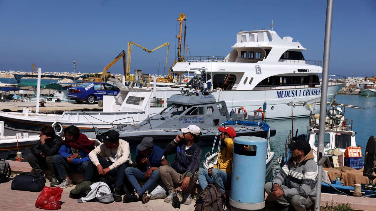 Migrants wait at a fishing shelter in Paralimni