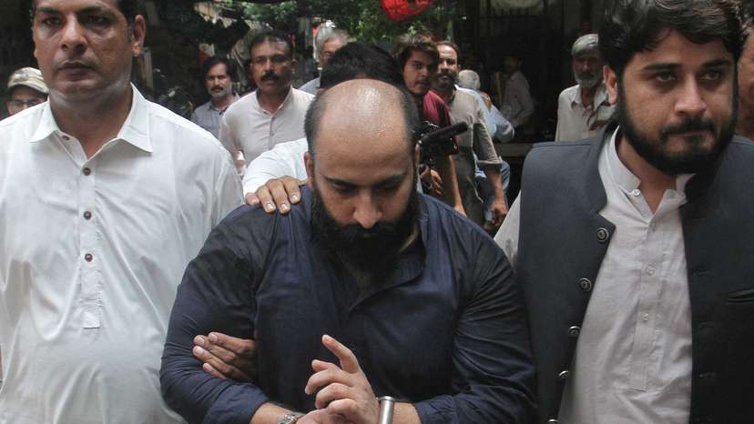 Farhan Asif is escorted by the members of FIA outside a court in Lahore