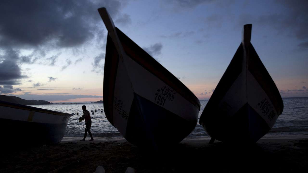 FILE PHOTO: A man walks past wooden boats in the bay of Rio Caribe a town near caribbean islands, in the eastern state of Sucre, Venezuela