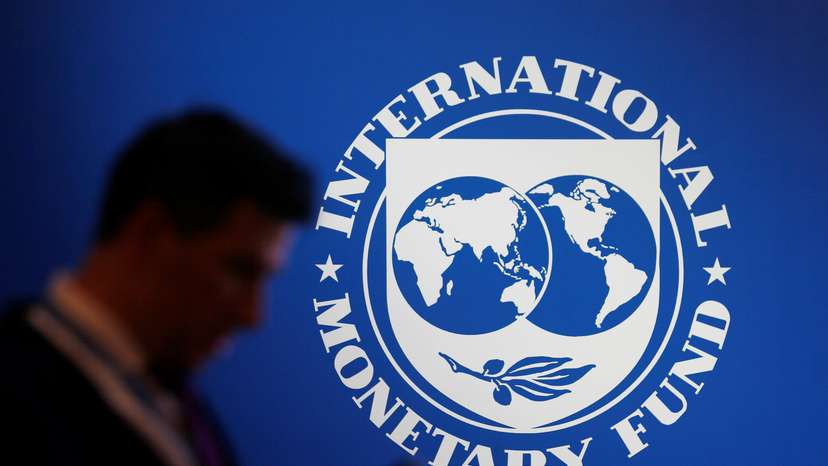 A participant stands near a logo of IMF at the International Monetary Fund - World Bank Annual Meeting 2018 in Nusa Dua