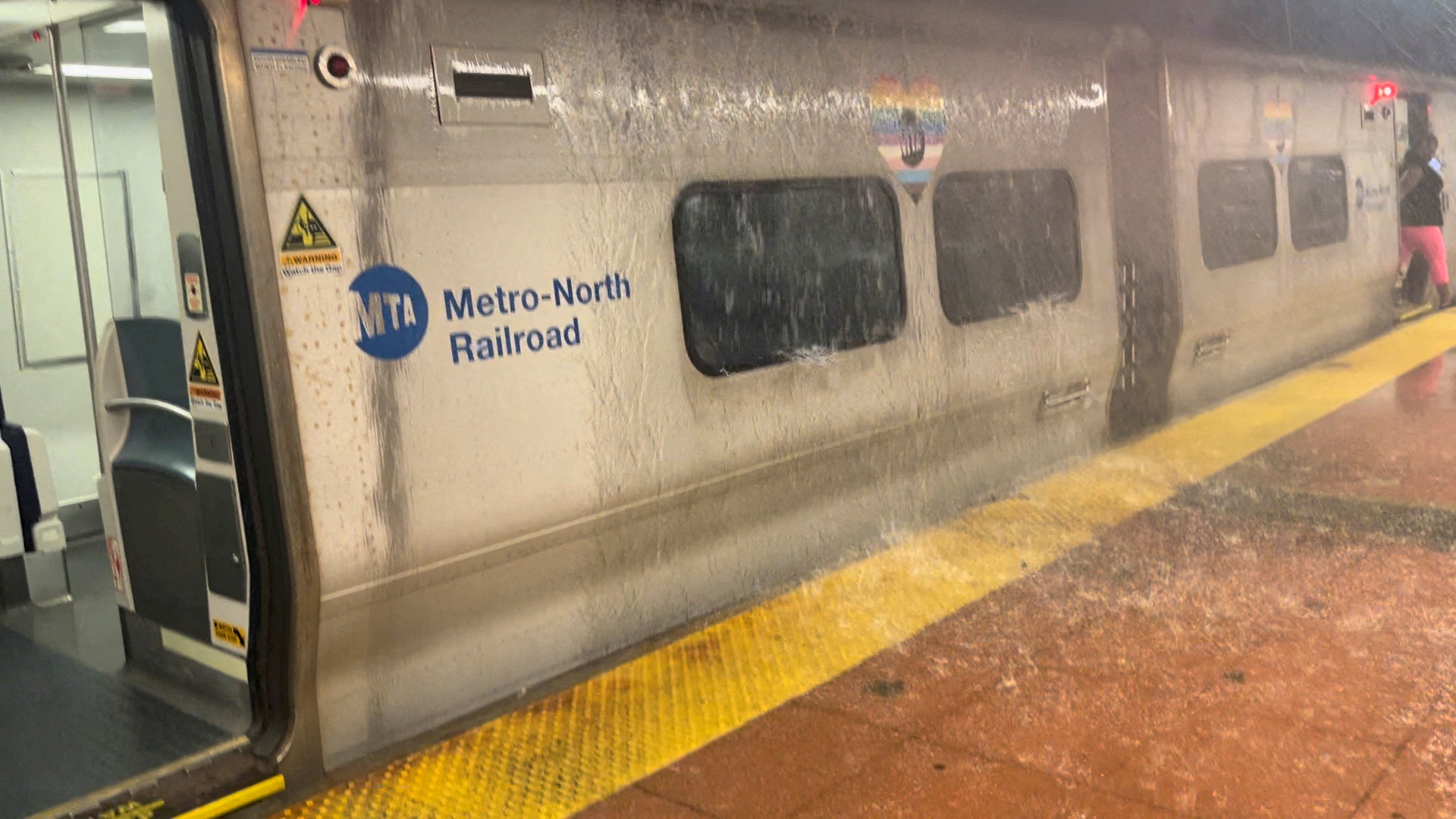 A woman steps off a train as rainwater pours onto a subway carriage in New York City