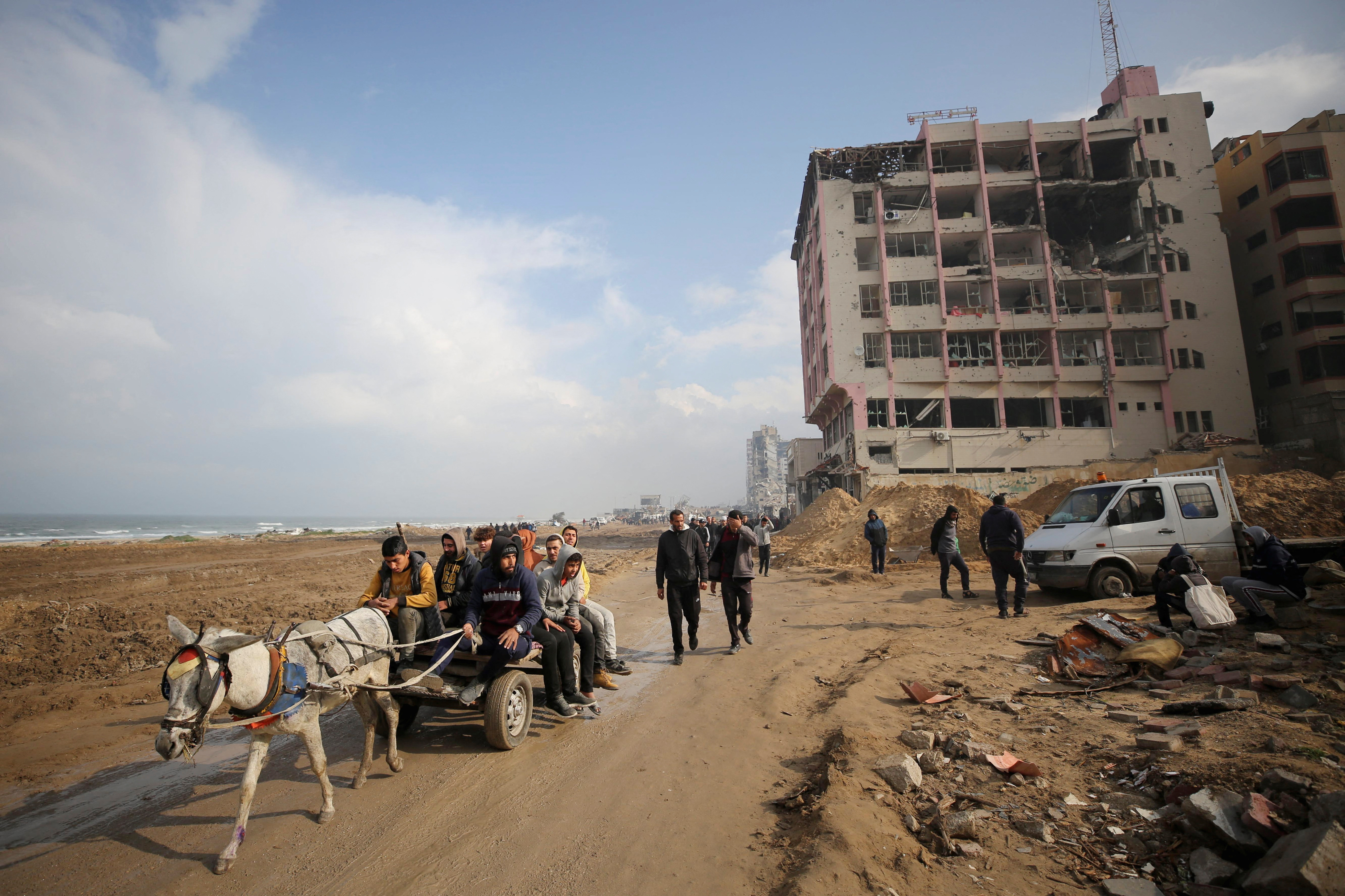 Palestinians ride a donkey cart through a destroyed beach road in Gaza City