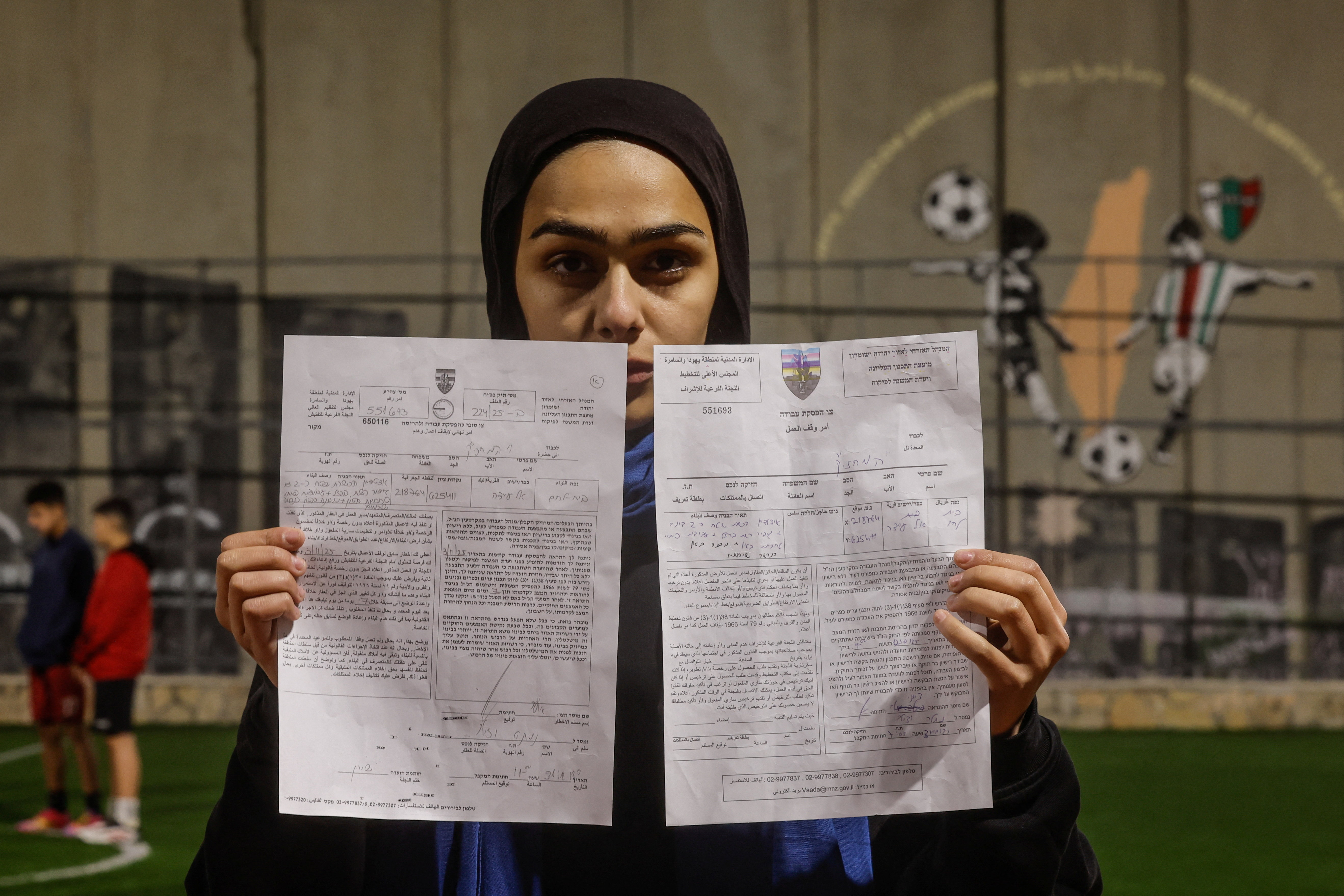 Palestinian teen holds demolition order of football field, in the Israeli-occupied city of Bethlehem