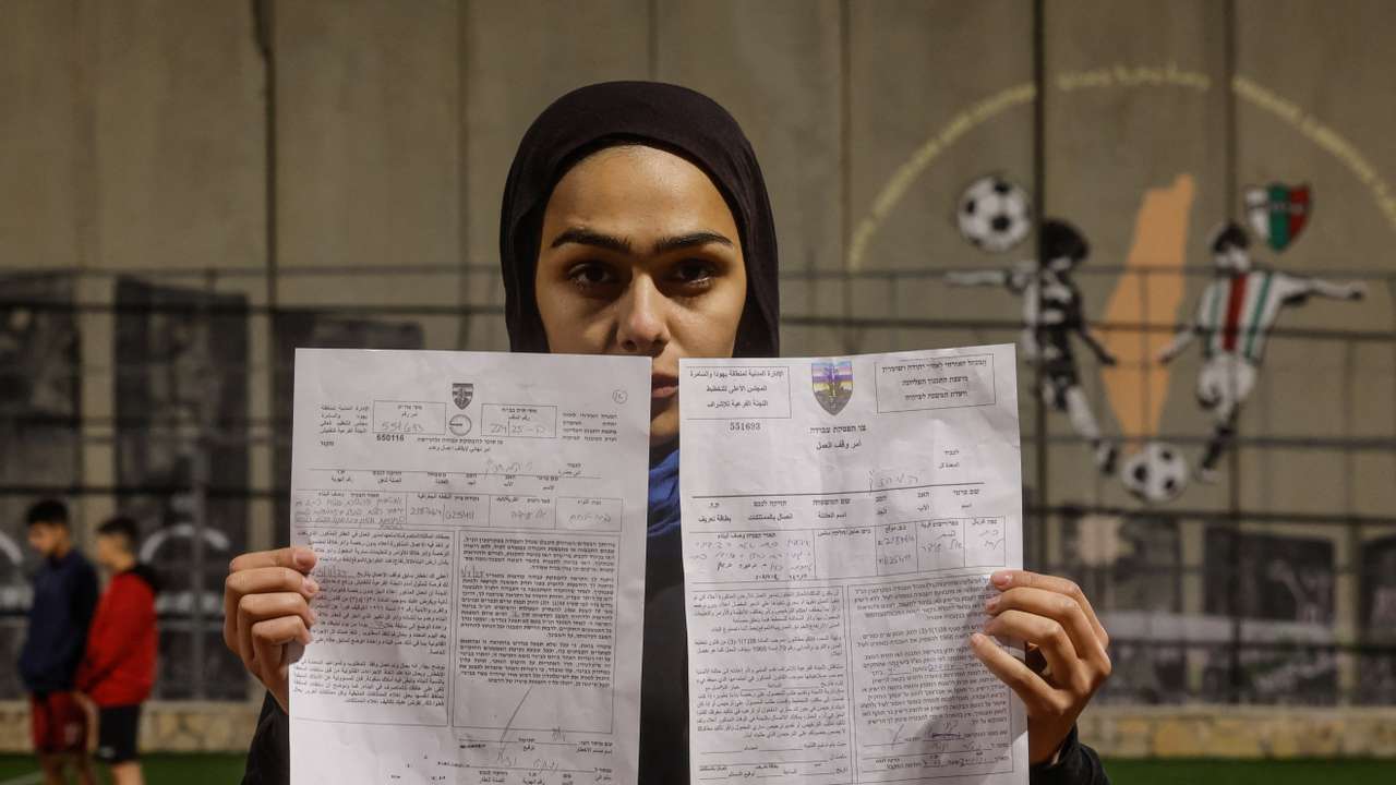 Palestinian teen holds demolition order of football field, in the Israeli-occupied city of Bethlehem