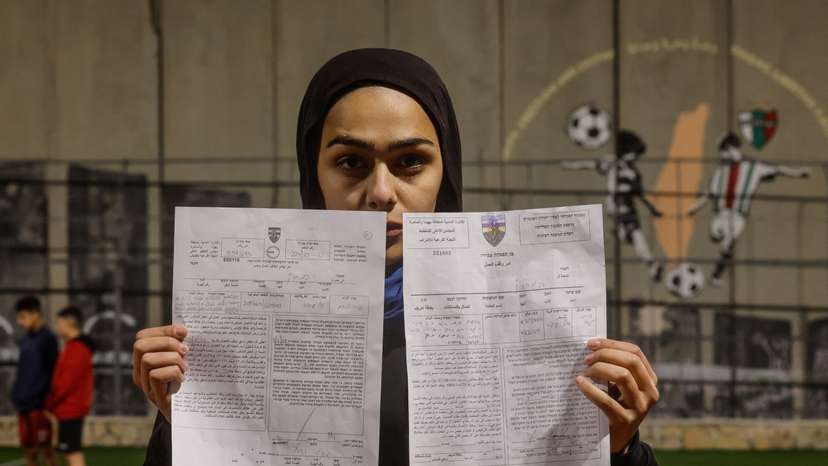 Palestinian teen holds demolition order of football field, in the Israeli-occupied city of Bethlehem