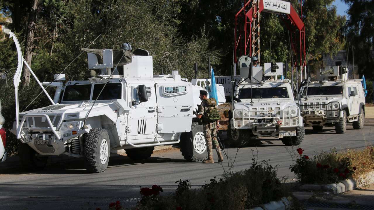Lebanese army soldier stands near UN peacekeepers (UNIFIL) vehicles in Marjayoun