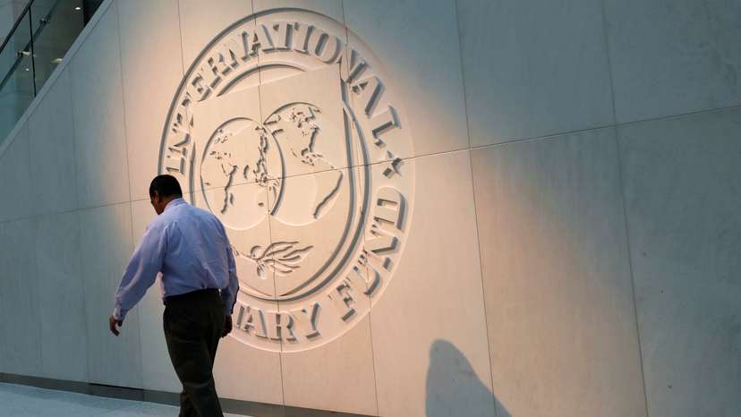 Man walks past the IMF logo at HQ in Washington