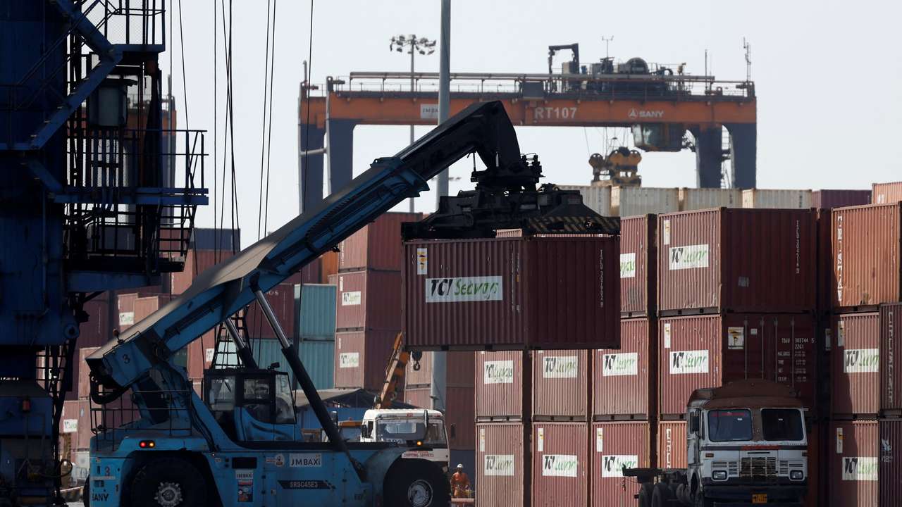 A mobile crane carries a container at Deendayal Port in Kandla