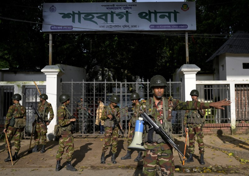 Security personnel stand guard next to a police station in Dhaka