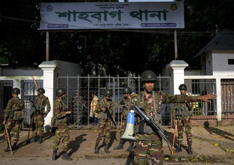 Security personnel stand guard next to a police station in Dhaka