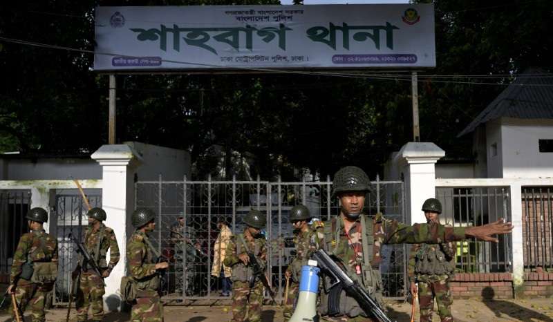 Security personnel stand guard next to a police station in Dhaka