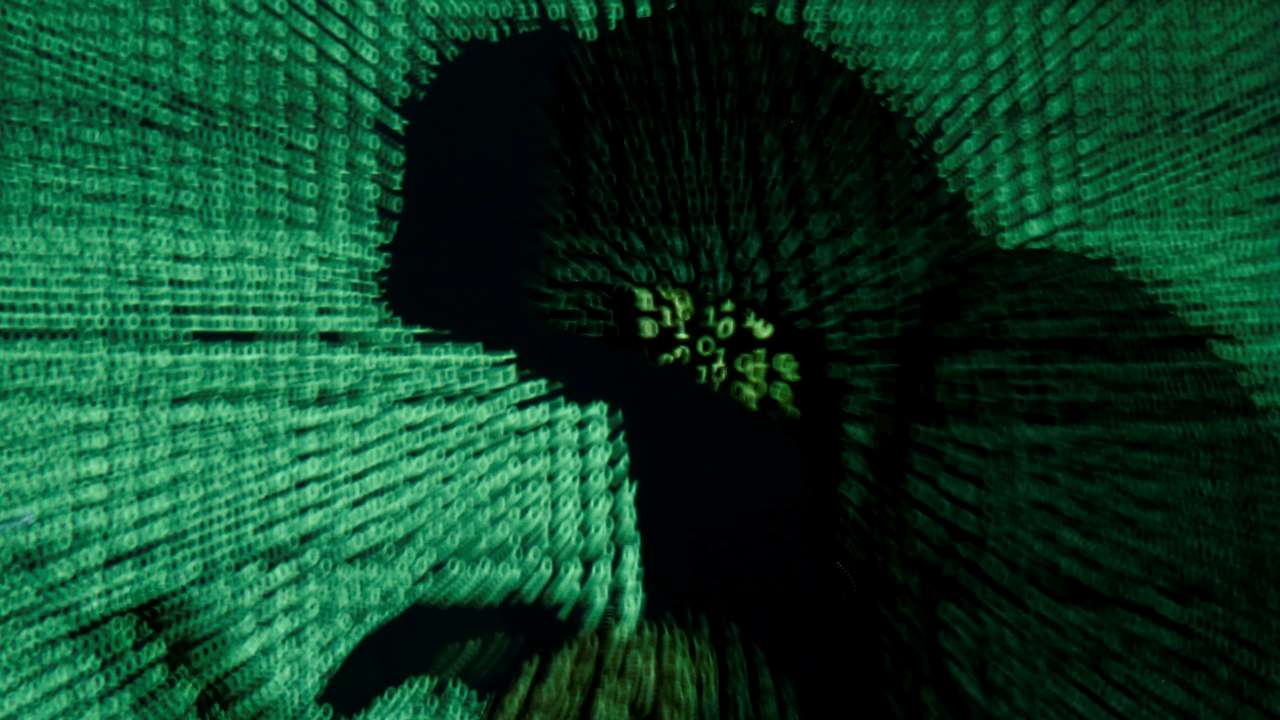 Man holds laptop computer as cyber code is projected on him in this illustration picture