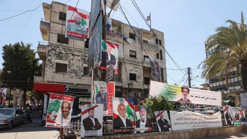 A banner depicting late Hezbollah leader Hassan Nasrallah and campaign poster of the candidates running for municipal elections, are placed along a street in Nabatieh