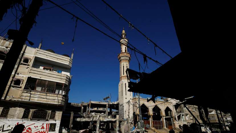 Palestinians stand near the site of an Israeli strike on a house, in Rafah