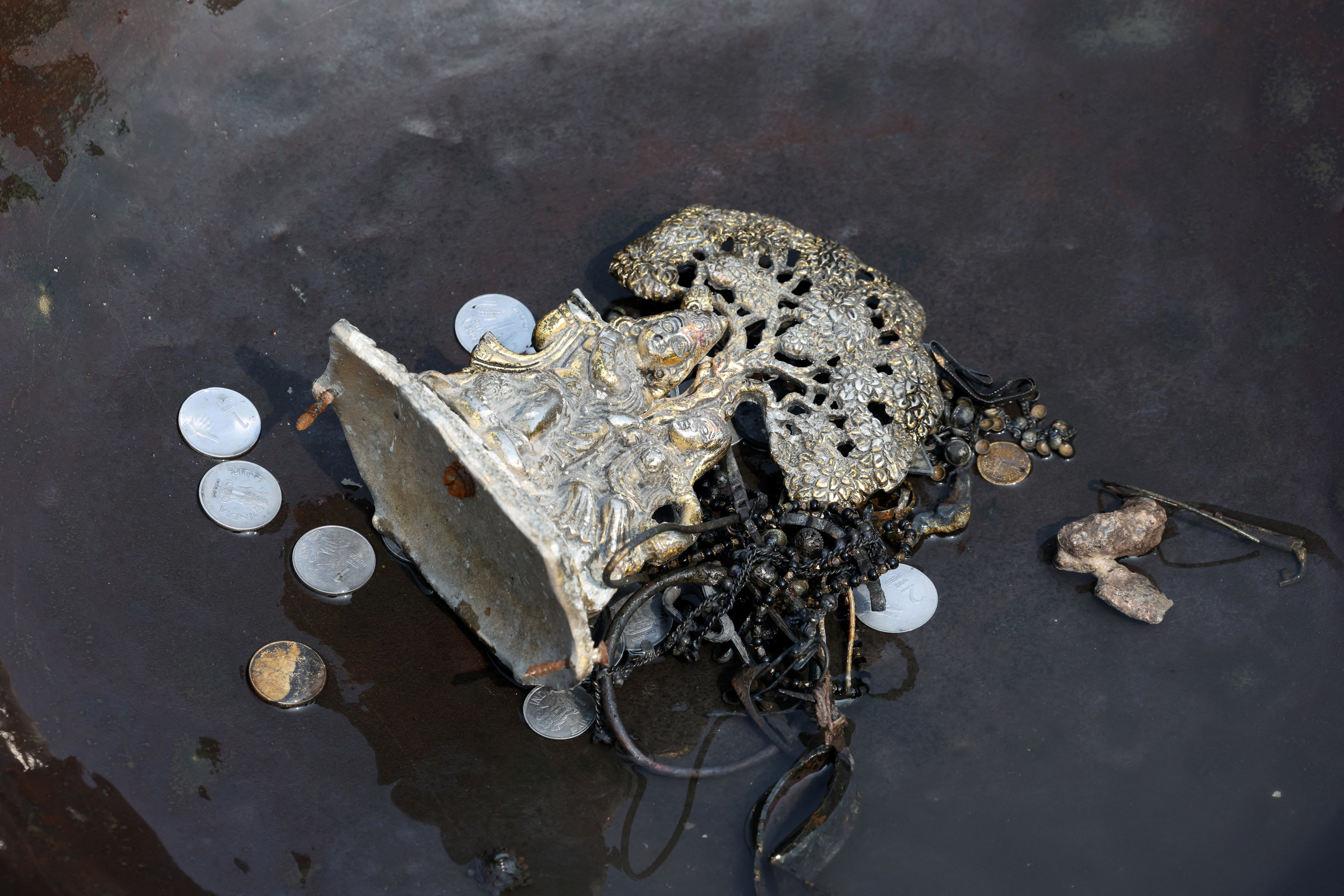 Items collected by people who go to the river to hunt for coins and other valuables from the waters of river Yamuna, are kept in a container
