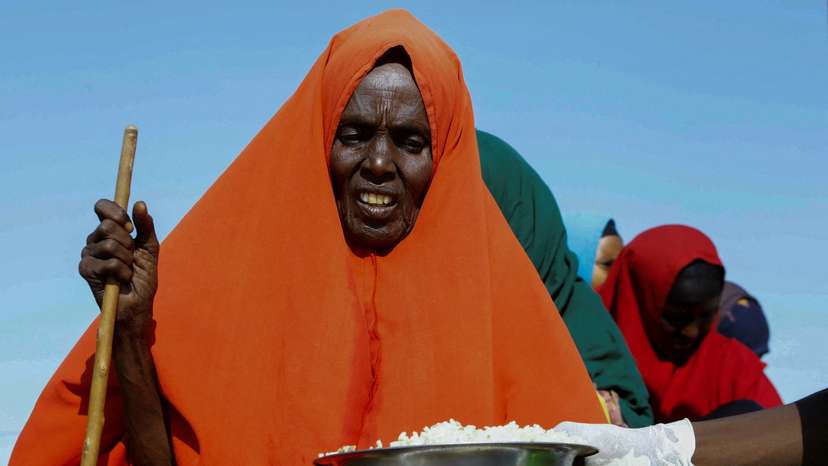 An internally displaced Somali woman receives iftar food rations for Ramadan, in the outskirt of Mogadishu