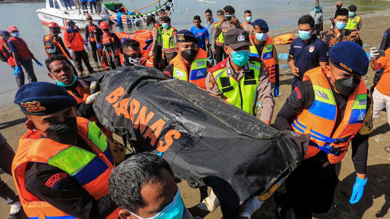 Rescuers carry body of Rohingya refugee recovered at sea after boat capsized off the coast near Calang