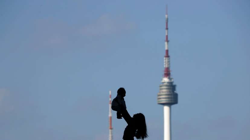 FILE PHOTO: A woman holding up her baby is silhouetted against the backdrop of N Seoul Tower in Seoul