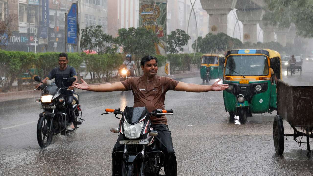 A man reacts during rainfall as the temperature dips in the capital upon the arrival of monsoon