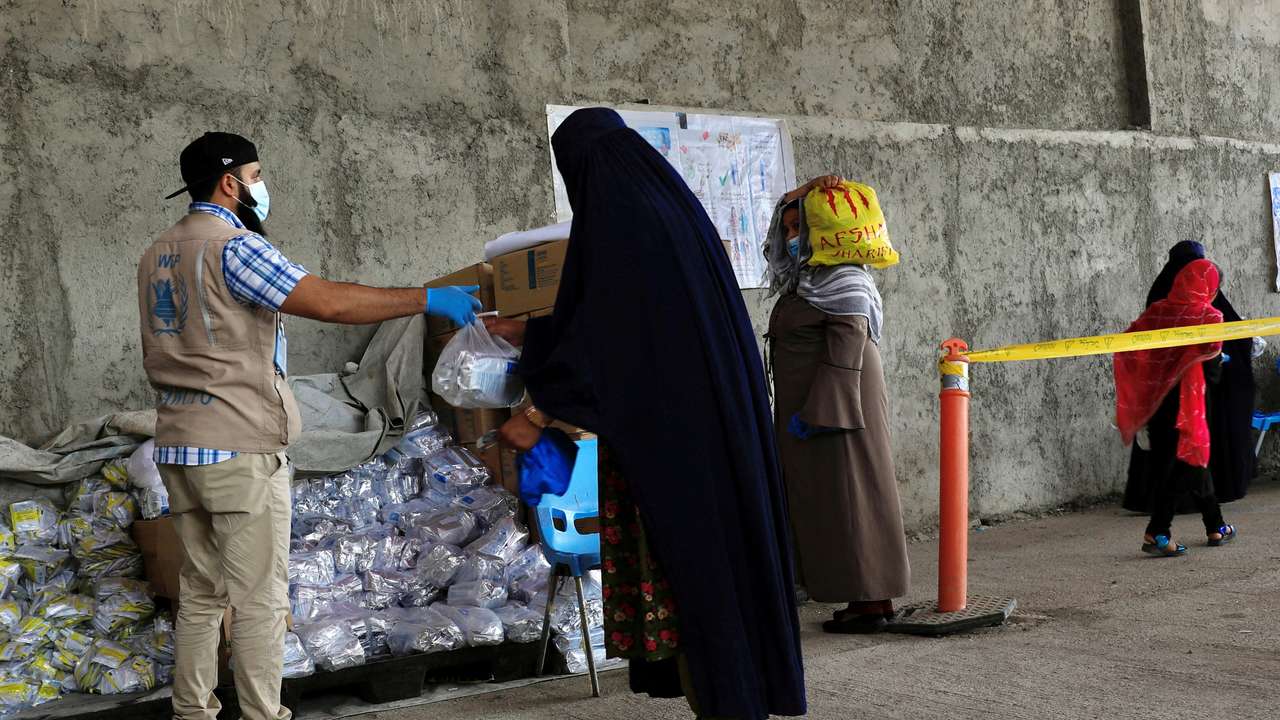 FILE PHOTO: An Afghan woman receives food items for her children at a World Food Program distribution centre in Kabul