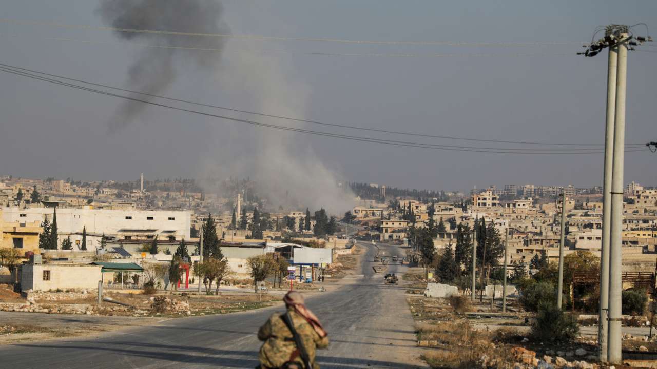 Smoke rises as a member of the rebels led by the Islamist militant group Hayat Tahrir al-Sham drives on a motorbike in al-Rashideen