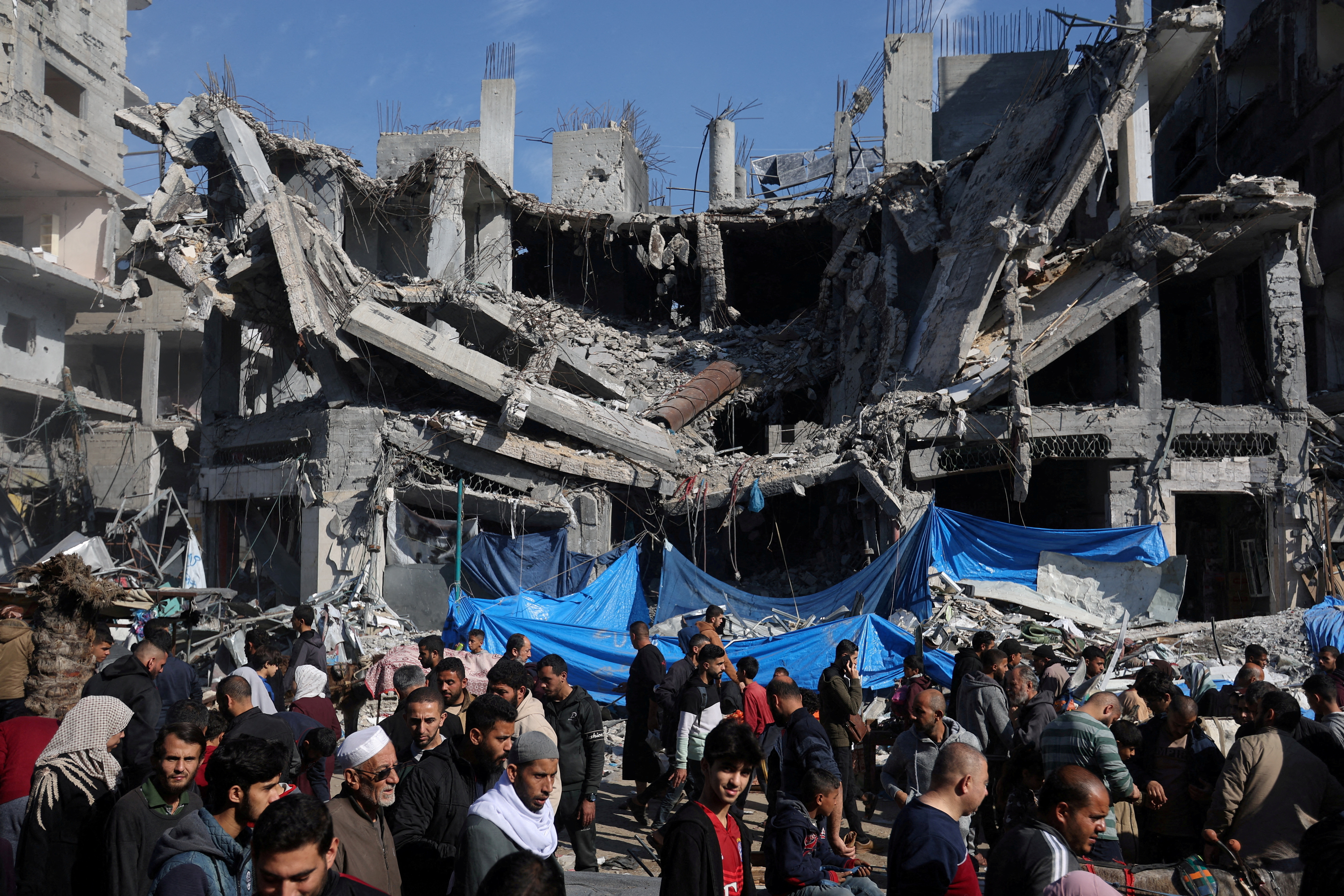 Palestinians shop near the ruins of houses and buildings destroyed in Israeli strikes during the conflict