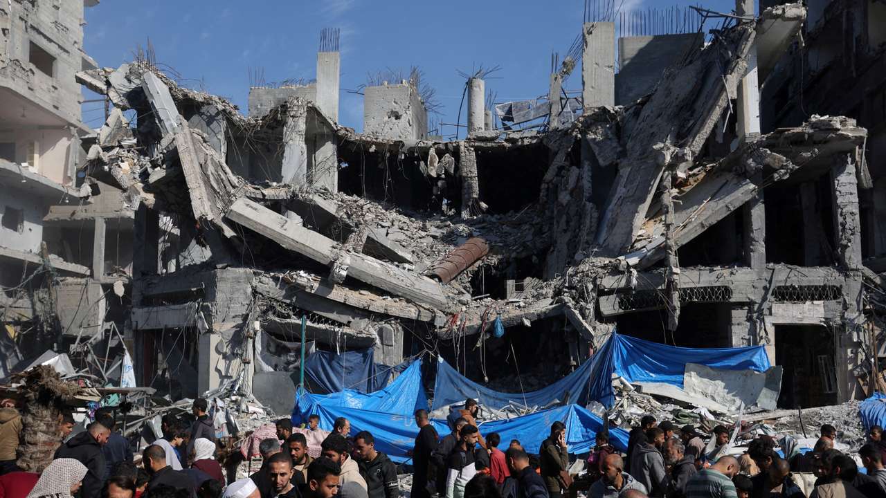 Palestinians shop near the ruins of houses and buildings destroyed in Israeli strikes during the conflict