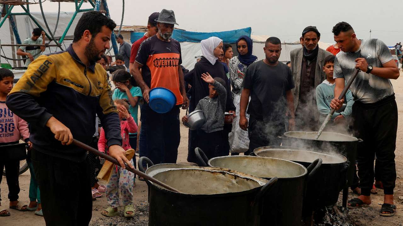 FILE PHOTO: Palestinians receive food cooked by a charity kitchen in Khan Younis, southern Gaza Strip
