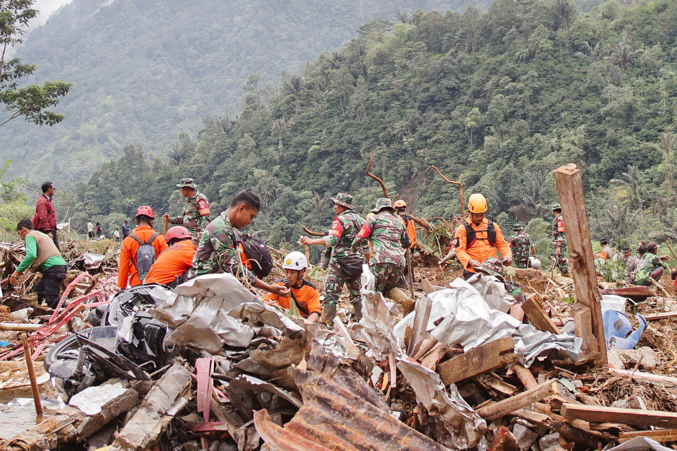 Indonesian rescue members and military officers search for victims at the site of a landslide caused by heavy rains in Pekalongan