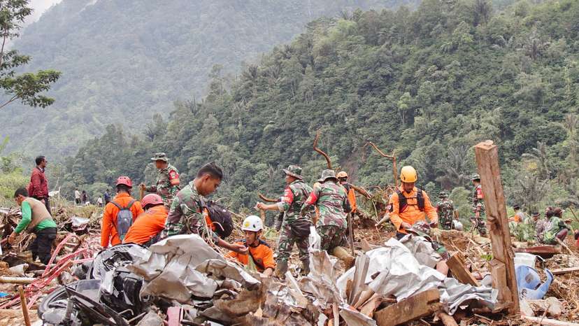 Indonesian rescue members and military officers search for victims at the site of a landslide caused by heavy rains in Pekalongan