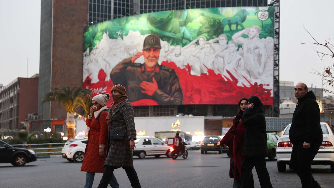 People walk on a street as protests erupt over the collapse of the currency's value in Tehran
