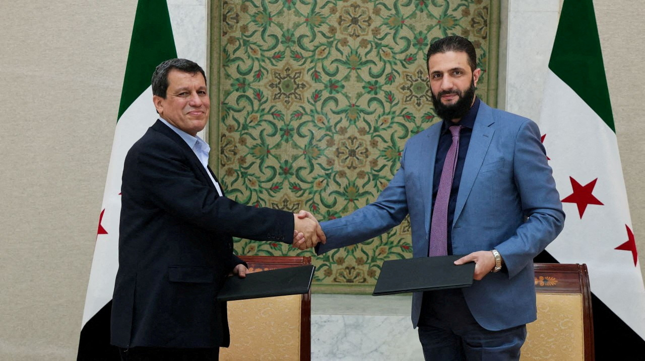 Syria's interim President Ahmed al-Sharaa and Commander of Syrian Kurdish-led forces Mazloum Abdi shake hands in Damascus