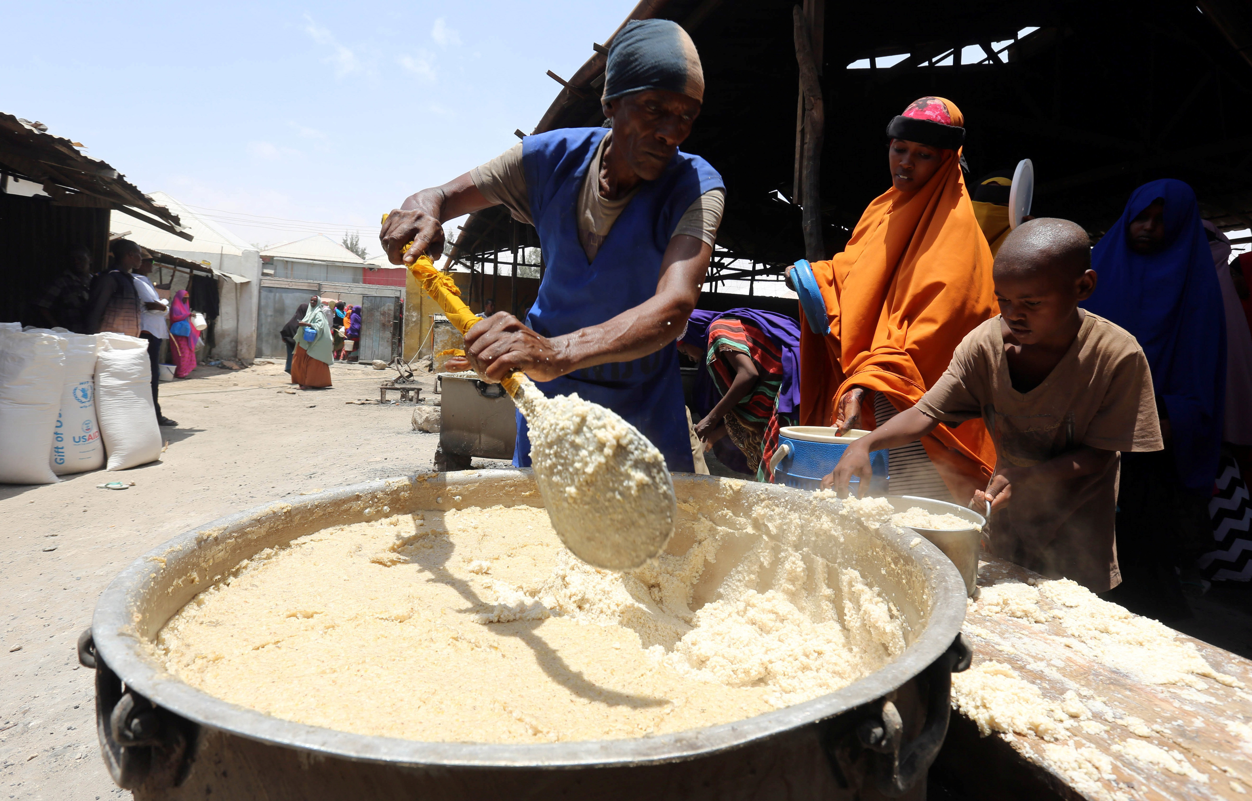 A volunteer serves internally displaced Somali people with cooked food from the WFP feeding program at the Sorrdo camp in Hodan district of Somalia's capital Mogadishu