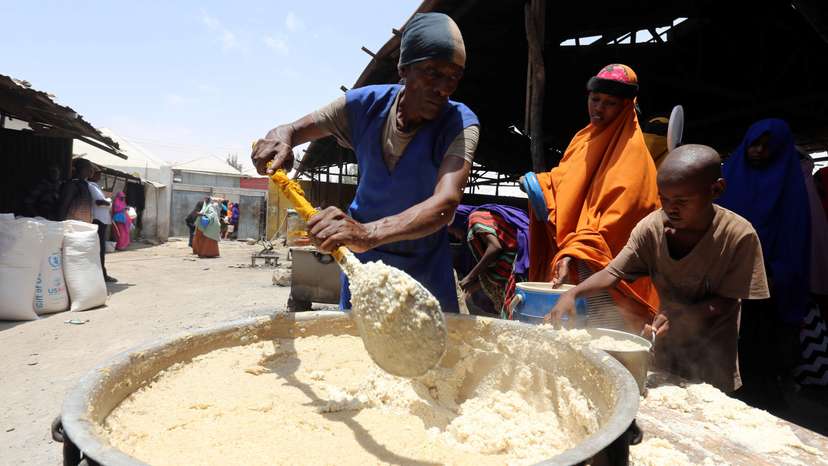 A volunteer serves internally displaced Somali people with cooked food from the WFP feeding program at the Sorrdo camp in Hodan district of Somalia's capital Mogadishu