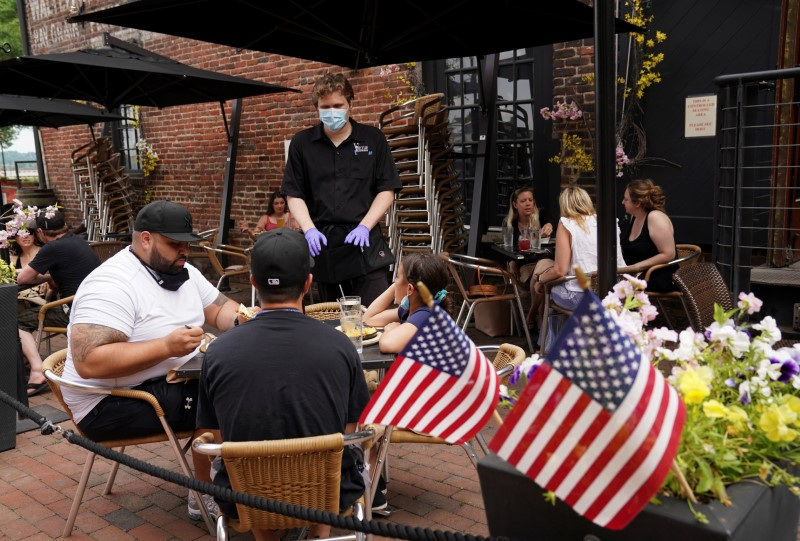 A waiter serves diners seated outdoors at a restaurant in Alexandria, Virginia, U.S., May 29, 2020. REUTERS/Kevin Lamarque/File photo