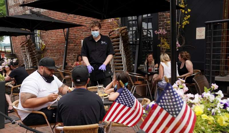 A waiter serves diners seated outdoors at a restaurant in Alexandria, Virginia, U.S., May 29, 2020. REUTERS/Kevin Lamarque/File photo