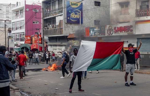 Supporters of opposition parties hold a national flag as they gesture in a sign of non-violence while walking towards the riot police officers during a protest ahead of the forthcoming first round of Madagascar's presidential election in Antananarivo