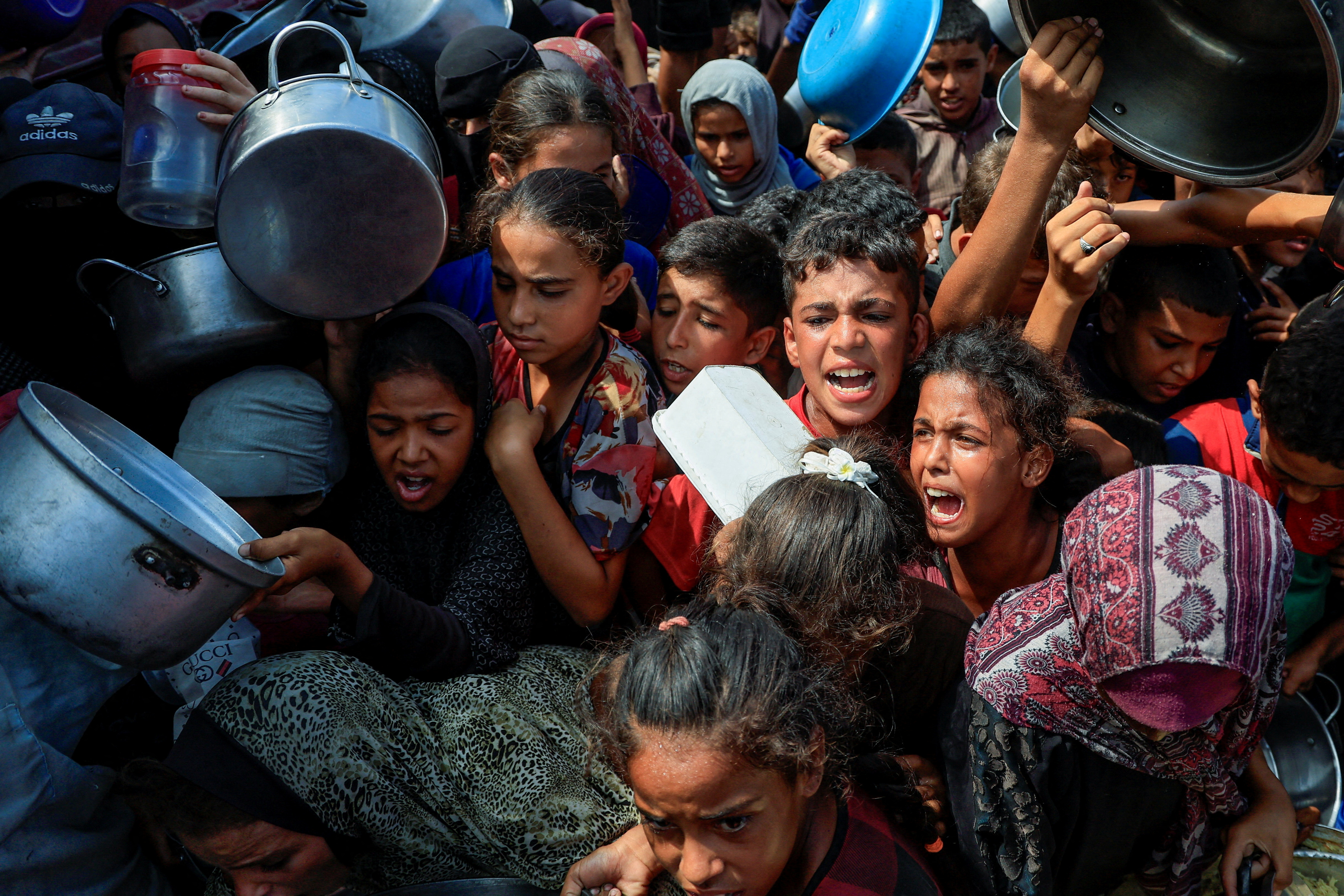 FILE PHOTO: Palestinians wait to receive food from a charity kitchen, in Khan Younis