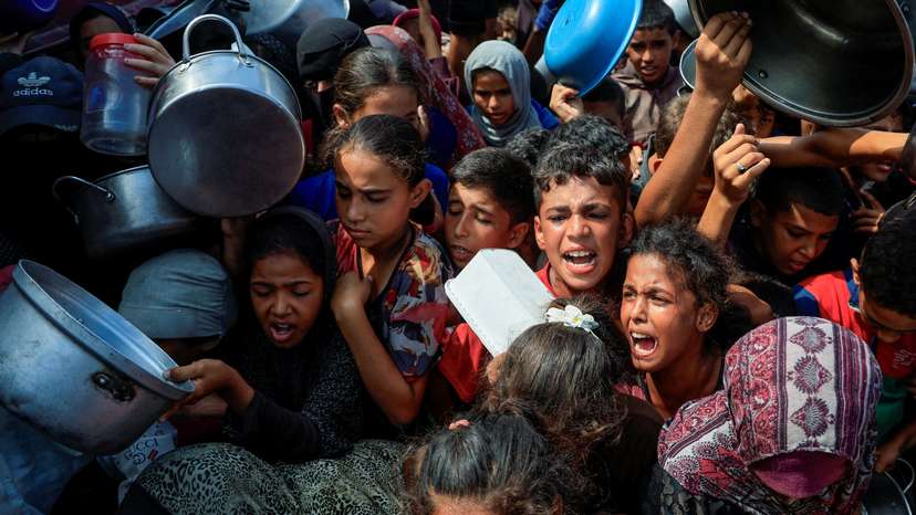 FILE PHOTO: Palestinians wait to receive food from a charity kitchen, in Khan Younis