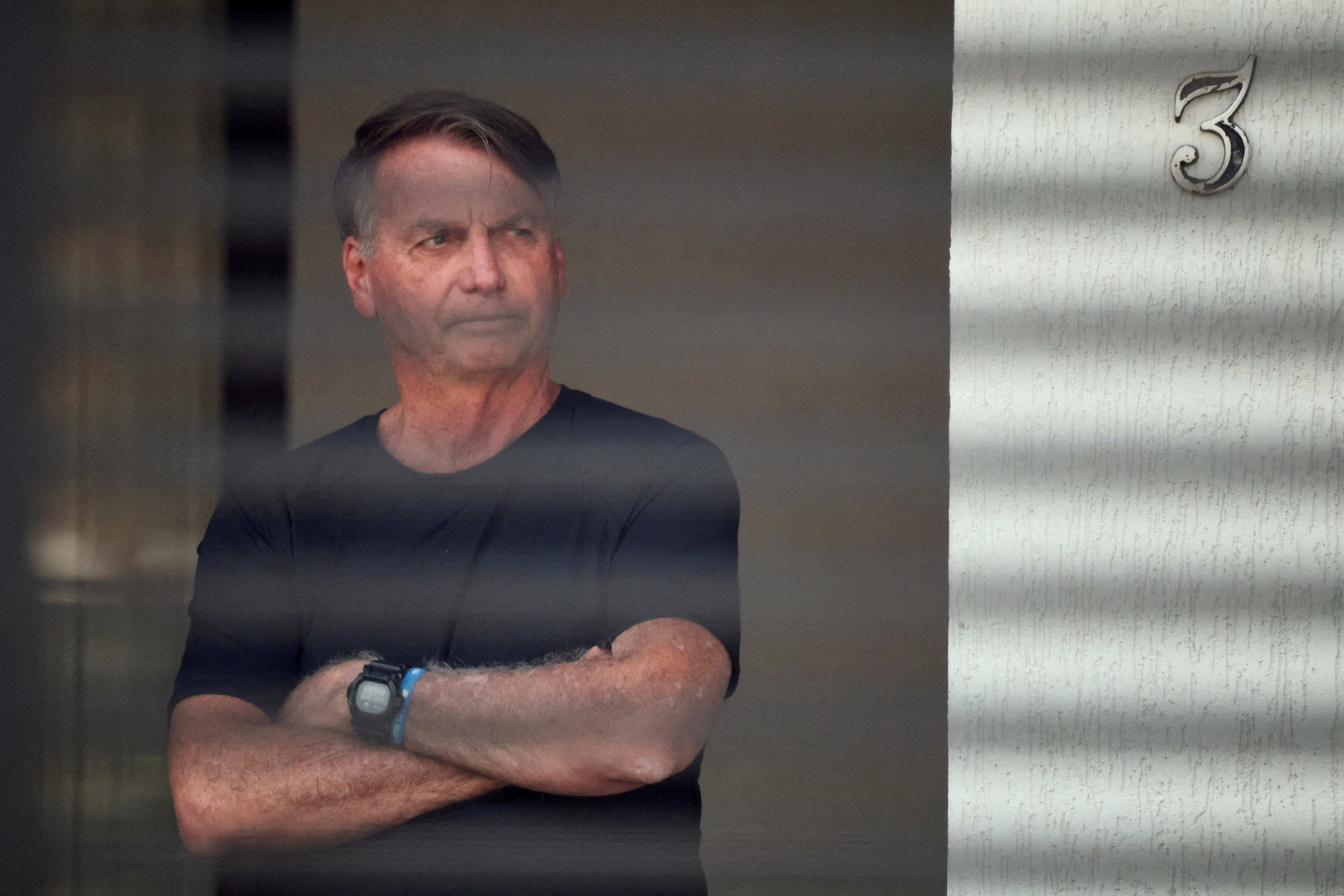 FILE PHOTO: Brazil’s former President Jair Bolsonaro stands at his home while under house arrest, in Brasilia