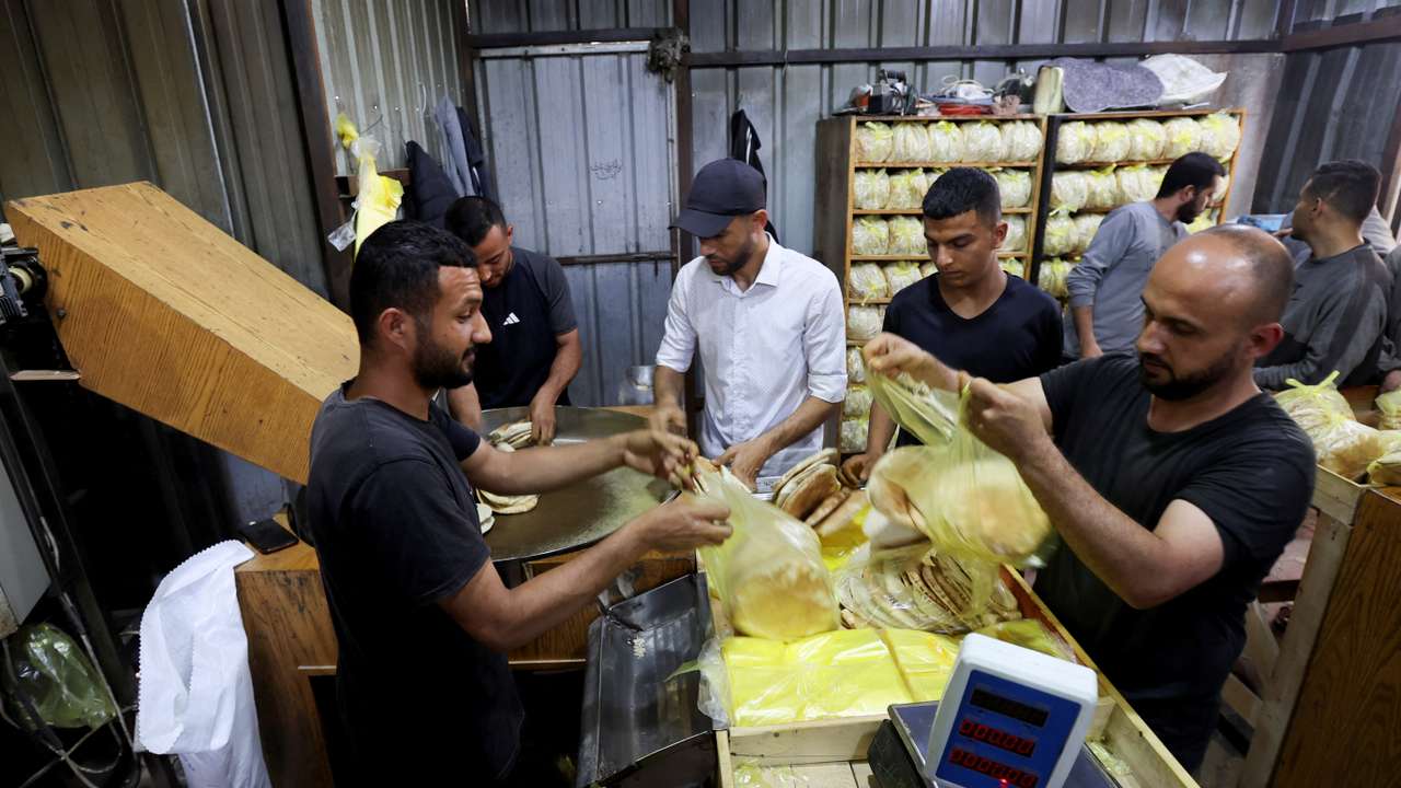 Palestinian workers pack bread in a bakery that returned to operation after being closed due to a flour shortage, in Deir Al-Balah
